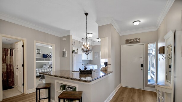 A kitchen with a central island, wooden flooring, and a chandelier. - Upscale Escape on Lake Conroe in April Sound! “On Lake Time” 3-2 on First Floor! (Montgomery)