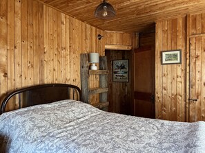 A wooden cabin room with a bed, a ladder, a lamp, and a poster on the wall. - Private Waterfront Family Cottage in Huntsville, Muskoka (Huntsville)