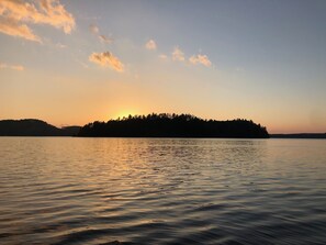 A calm lake at sunset with a silhouette of a forested island in the distance. - Private Waterfront Family Cottage in Huntsville, Muskoka (Huntsville)