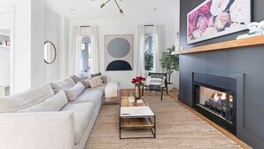 Una sala de estar moderna con chimenea, un sofá, una mesa de centro y un cuadro grande.