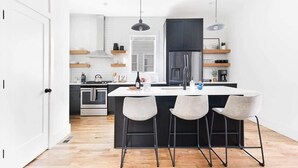 Una cocina moderna con una isla central, taburetes de bar y un refrigerador grande.