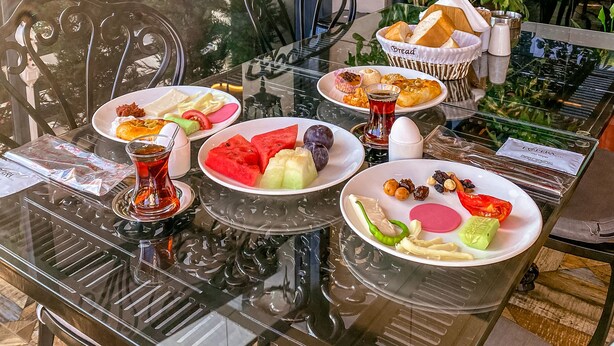 A dining table with various dishes, a glass coffee table, and chairs. - L'opera Deluxe Hotel (Edremit)