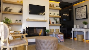A modern living room with a fireplace, television, and decorative shelves. - L'opera Deluxe Hotel (Edremit)