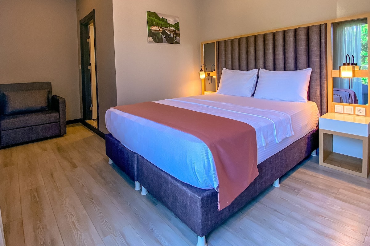 A modern bedroom with a large bed, a sofa, and a small table.