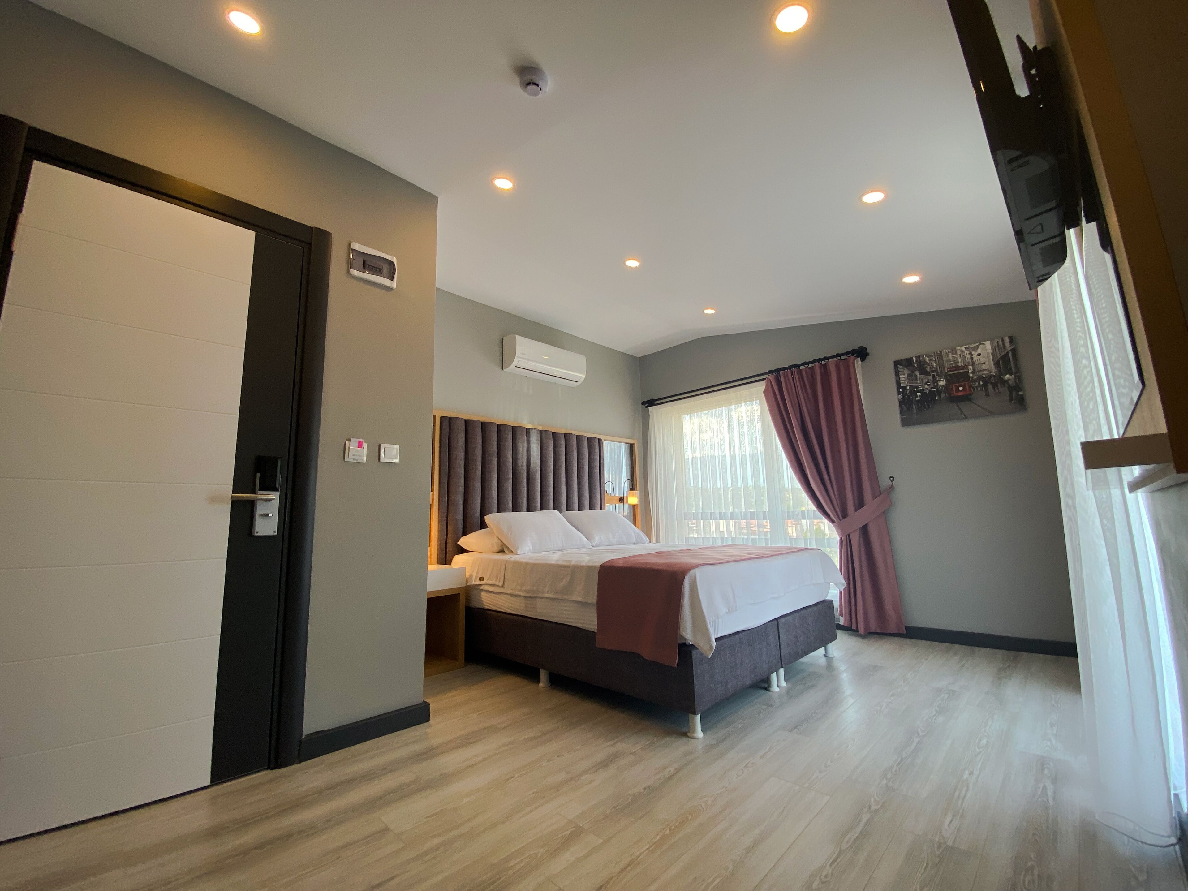 Quarto de hotel com cama, mesa de cabeceira e janela com cortinas.