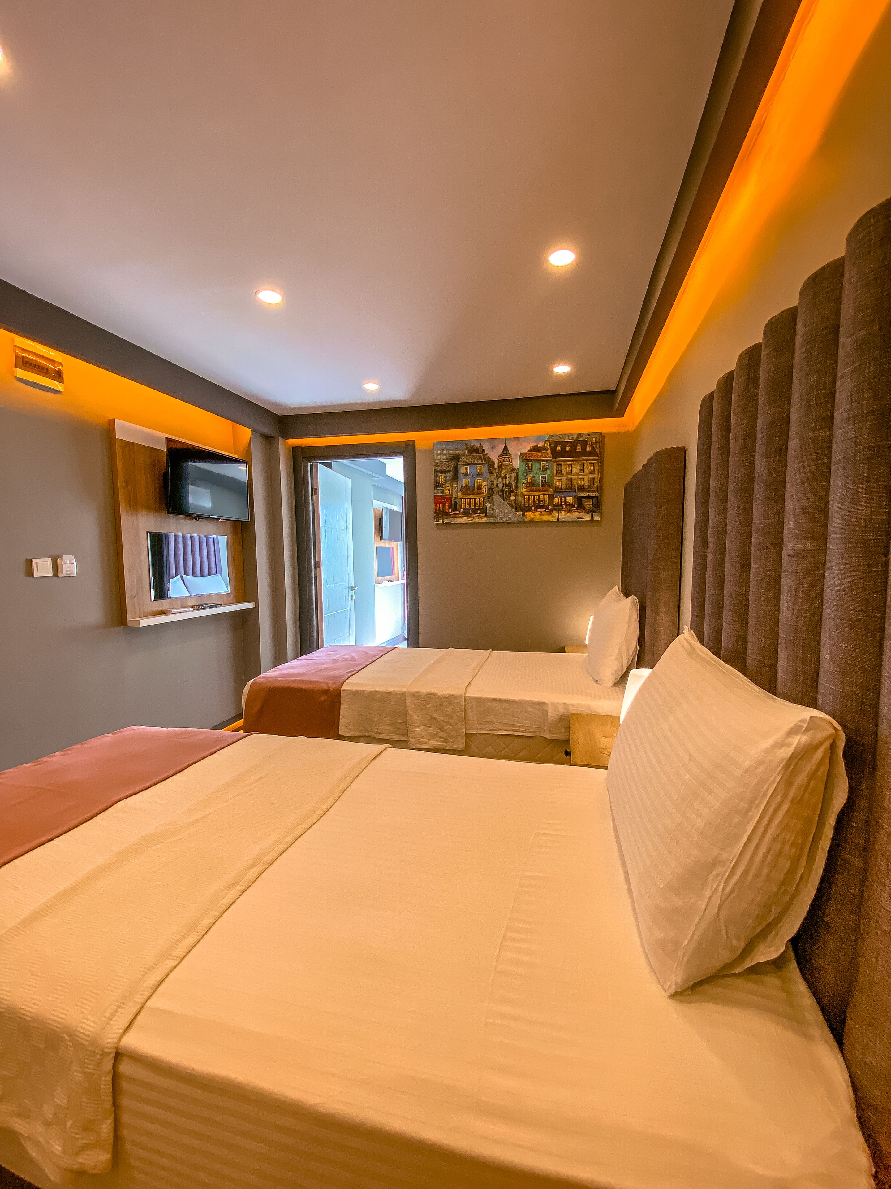Habitación de hotel con una cama grande, un televisor montado en la pared y un cuadro sobre la cama.