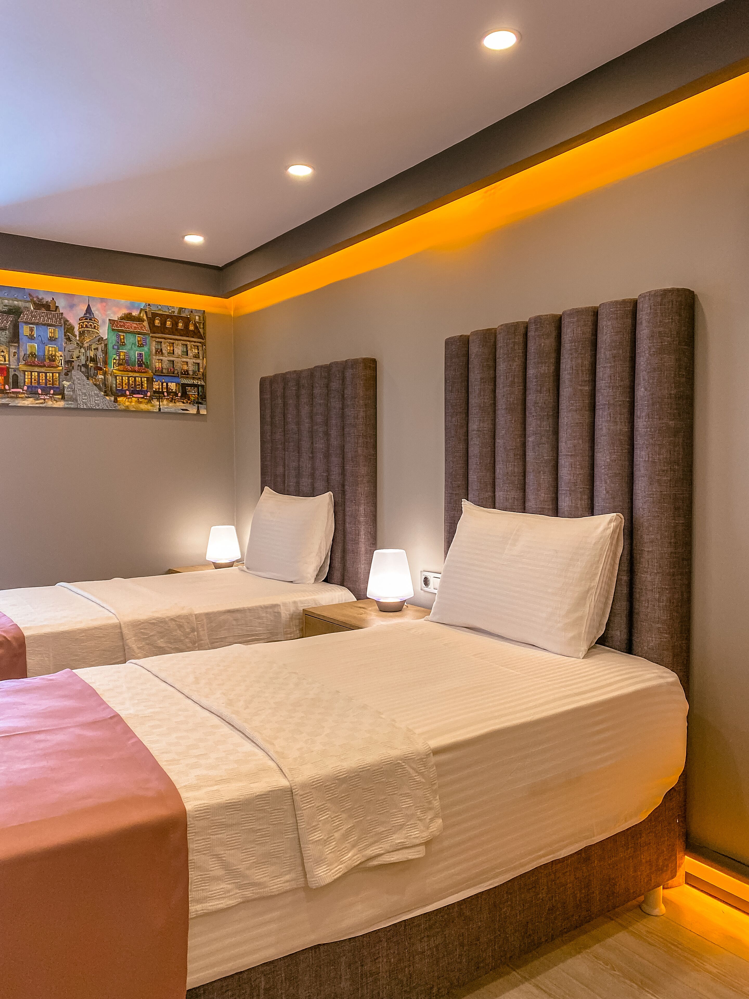 A hotel room with two beds, a painting on the wall, and a modern design.