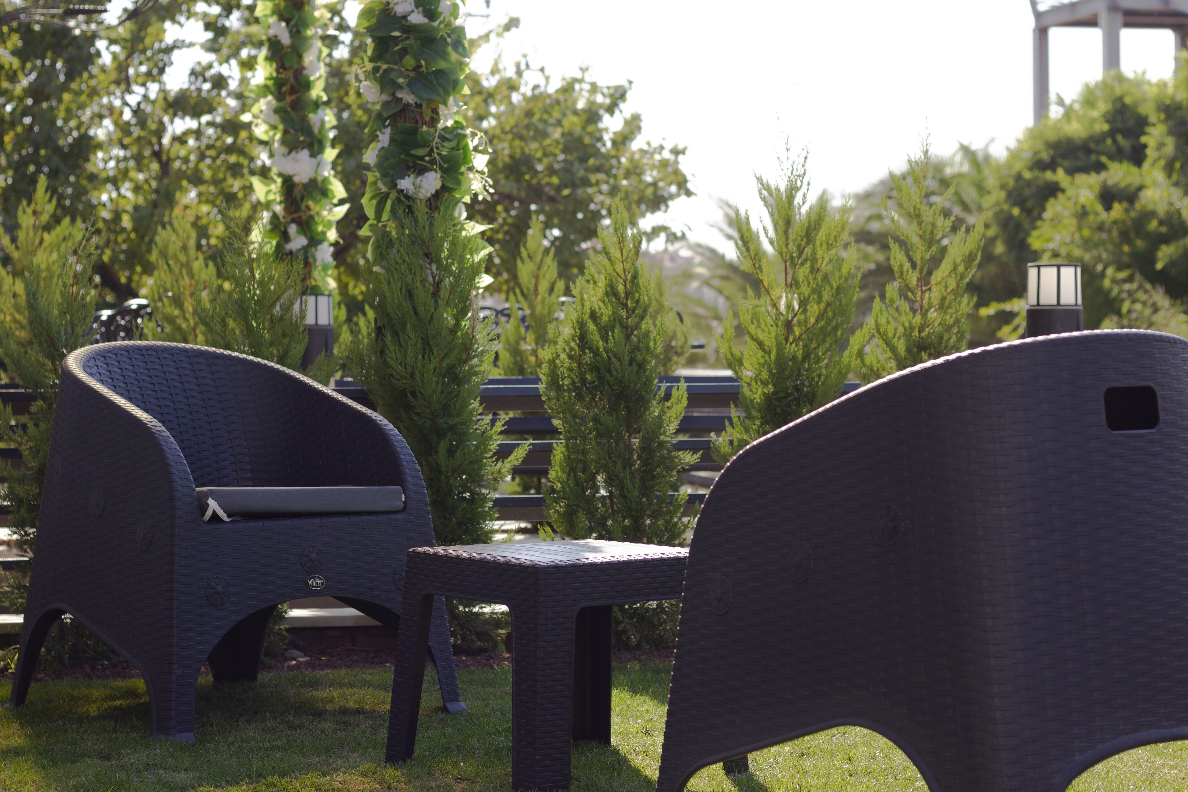 Two wicker chairs with a bench in a garden setting.