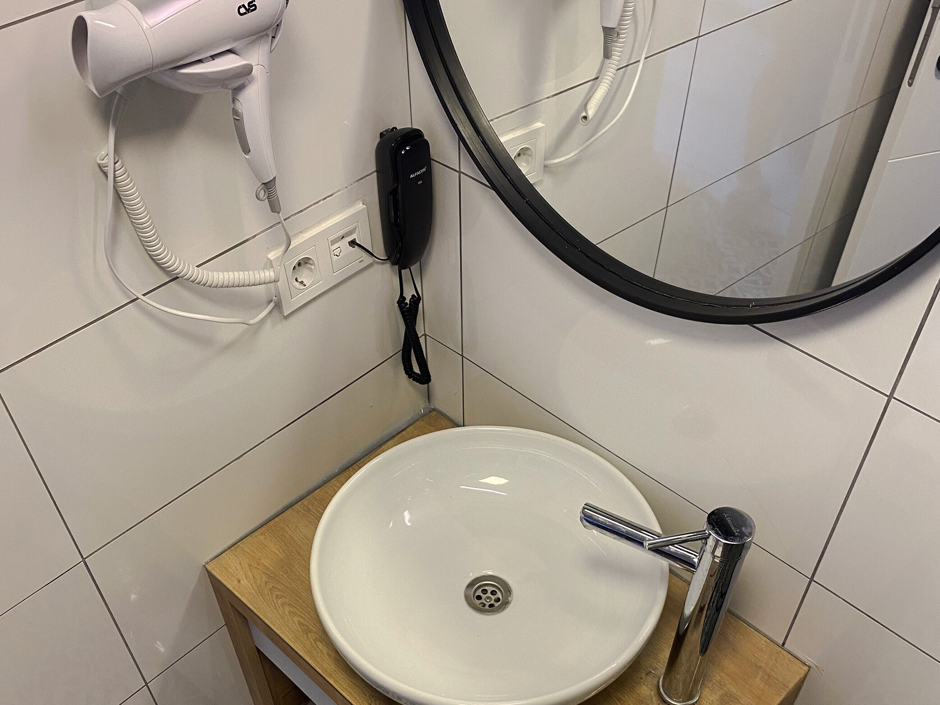 Ein Badezimmer mit Waschbecken, Fön, Telefon und Spiegel.