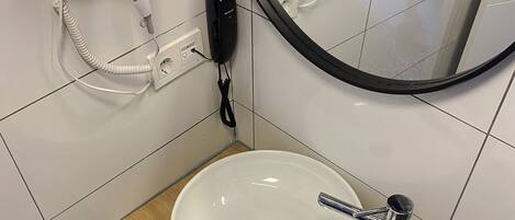 Ein Badezimmer mit Waschbecken, Fön, Telefon und Spiegel.