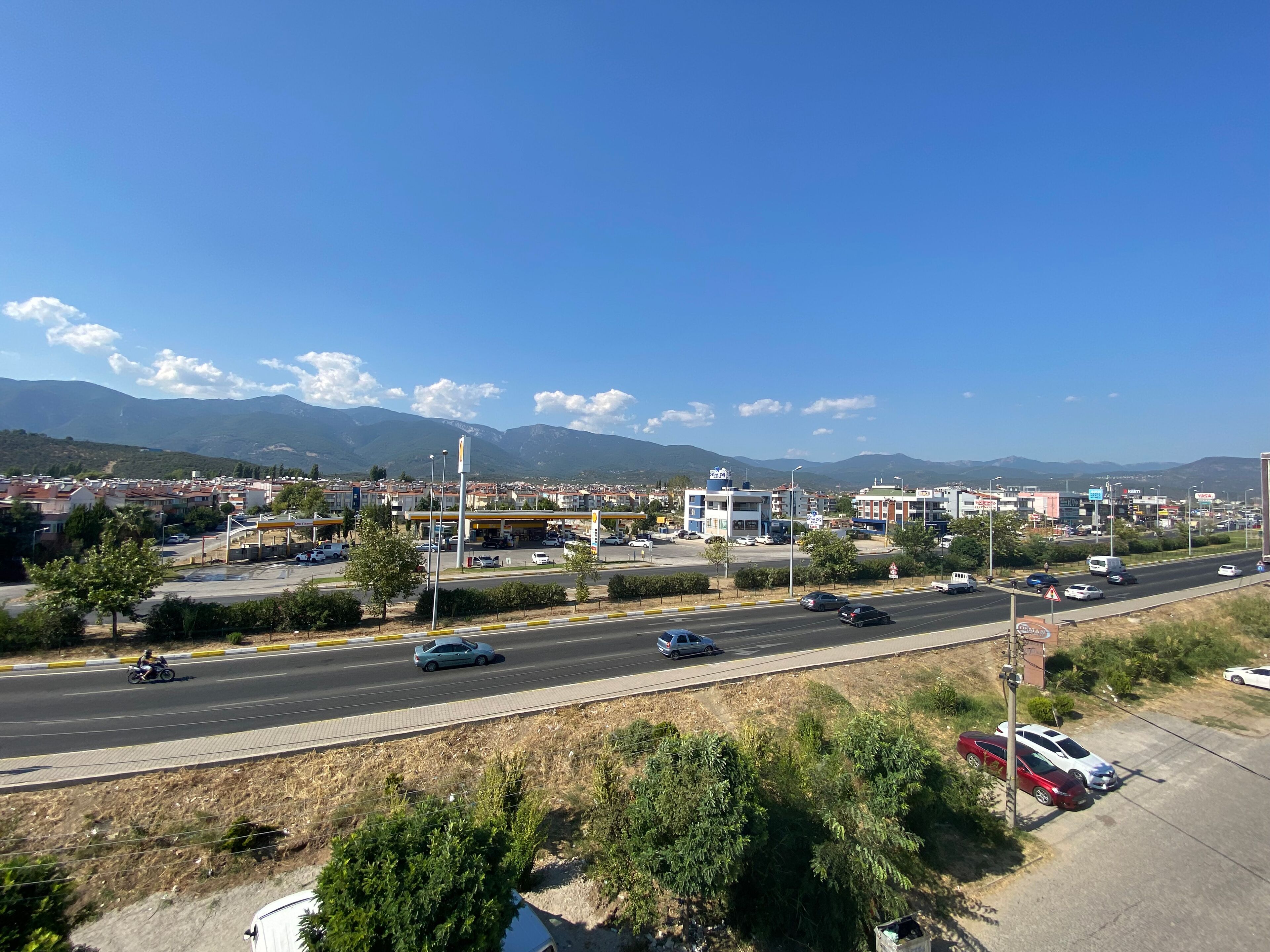 A highway with vehicles, a gas station, and buildings in the background.