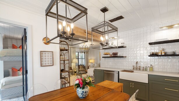 A modern kitchen with wooden cabinets, a dining table, and pendant lights. - Le Hibou Blanc (A) - Fairhope: Laid-back Sophistication (Fairhope)