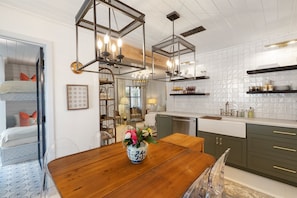 A modern kitchen with wooden cabinets, a dining table, and pendant lights.