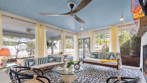 A spacious room with a ceiling fan, a glass coffee table, and a sofa with striped cushions. - Le Hibou Blanc (A) - Fairhope: Laid-back Sophistication (Fairhope)