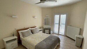 A bedroom with a bed, bedside tables, a dresser, a mirror, and a ceiling fan.