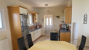 A kitchen with a dining table, chairs, a refrigerator, and a microwave.