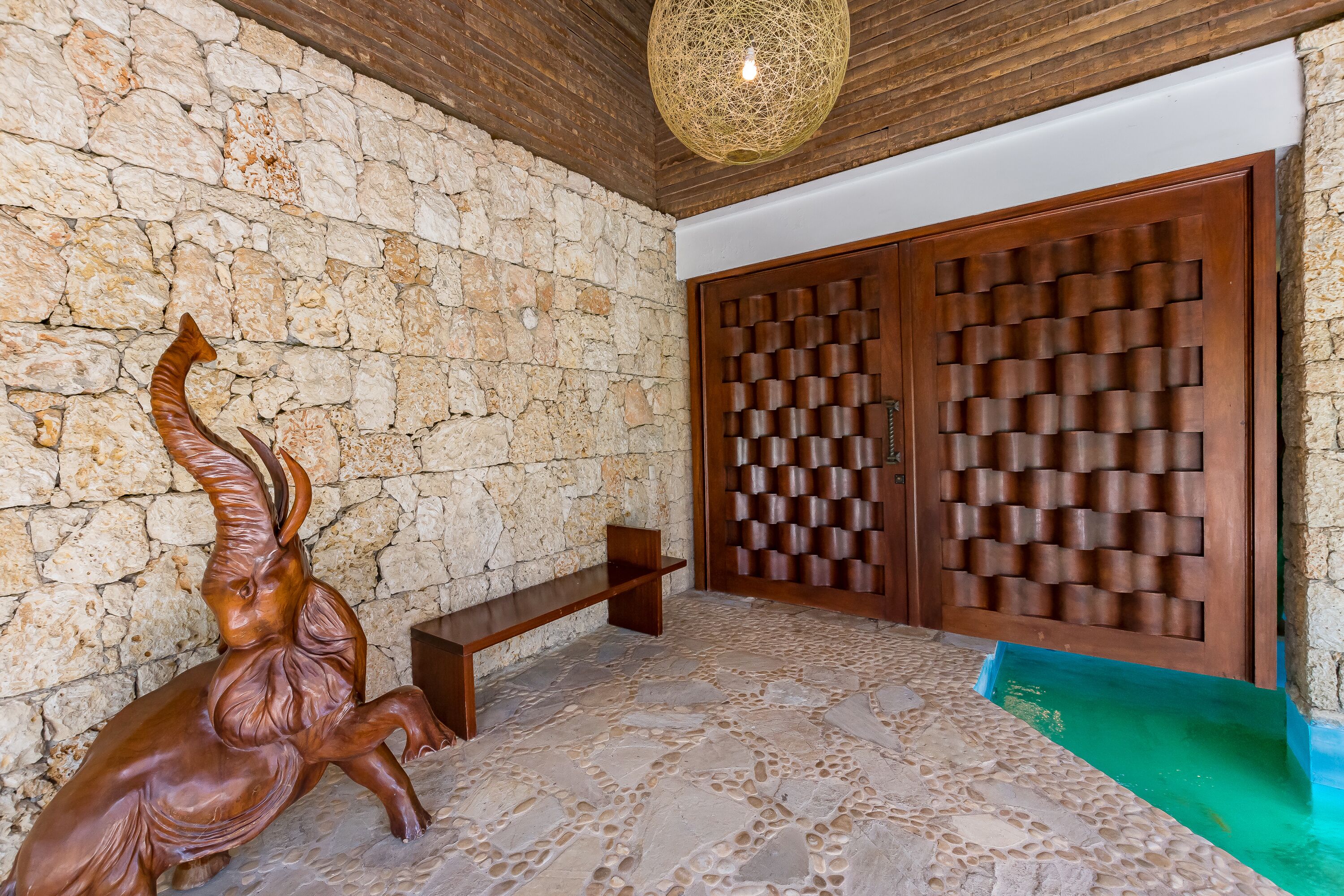 A stone wall, a wooden bench, and a door with a patterned design.