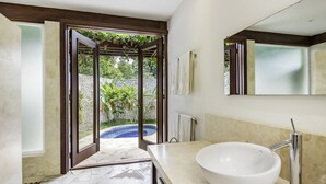Un bany amb un gran mànec blanc, un mirall i vista a una piscina per una porta oberta.