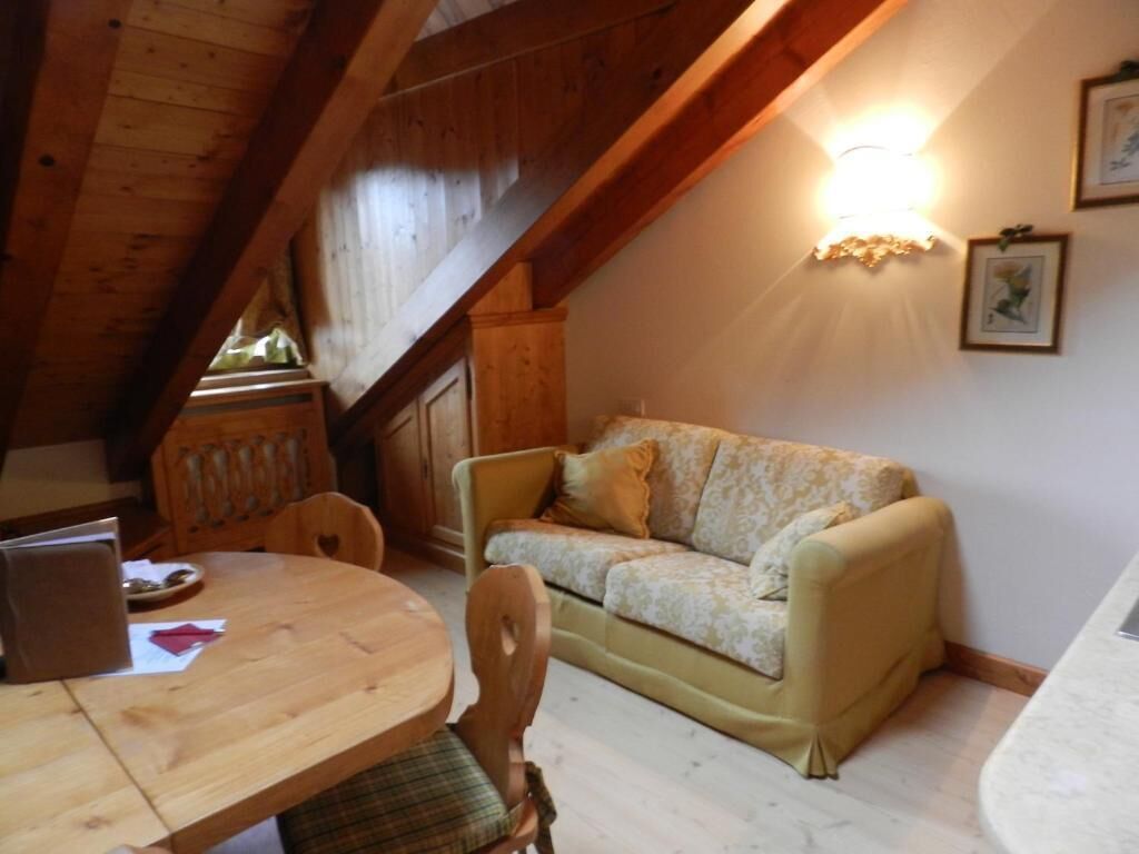 A cozy room with a wooden ceiling, a sofa, a dining table, and a wall-mounted light fixture.