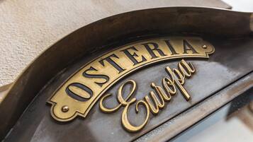 A brass plaque with the inscription "OSTERIA Europa" on a dark, curved surface.