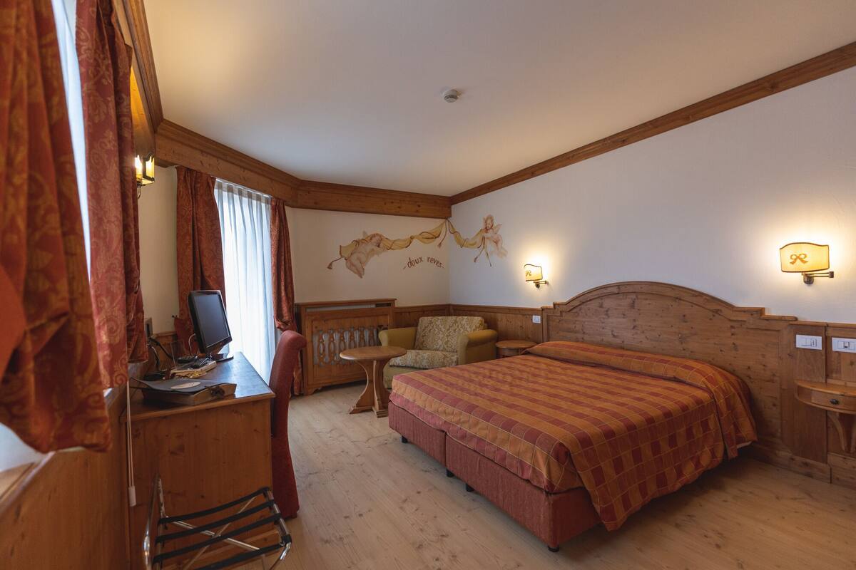 A cozy room with a bed, a desk with a computer, a chair, and a small table.