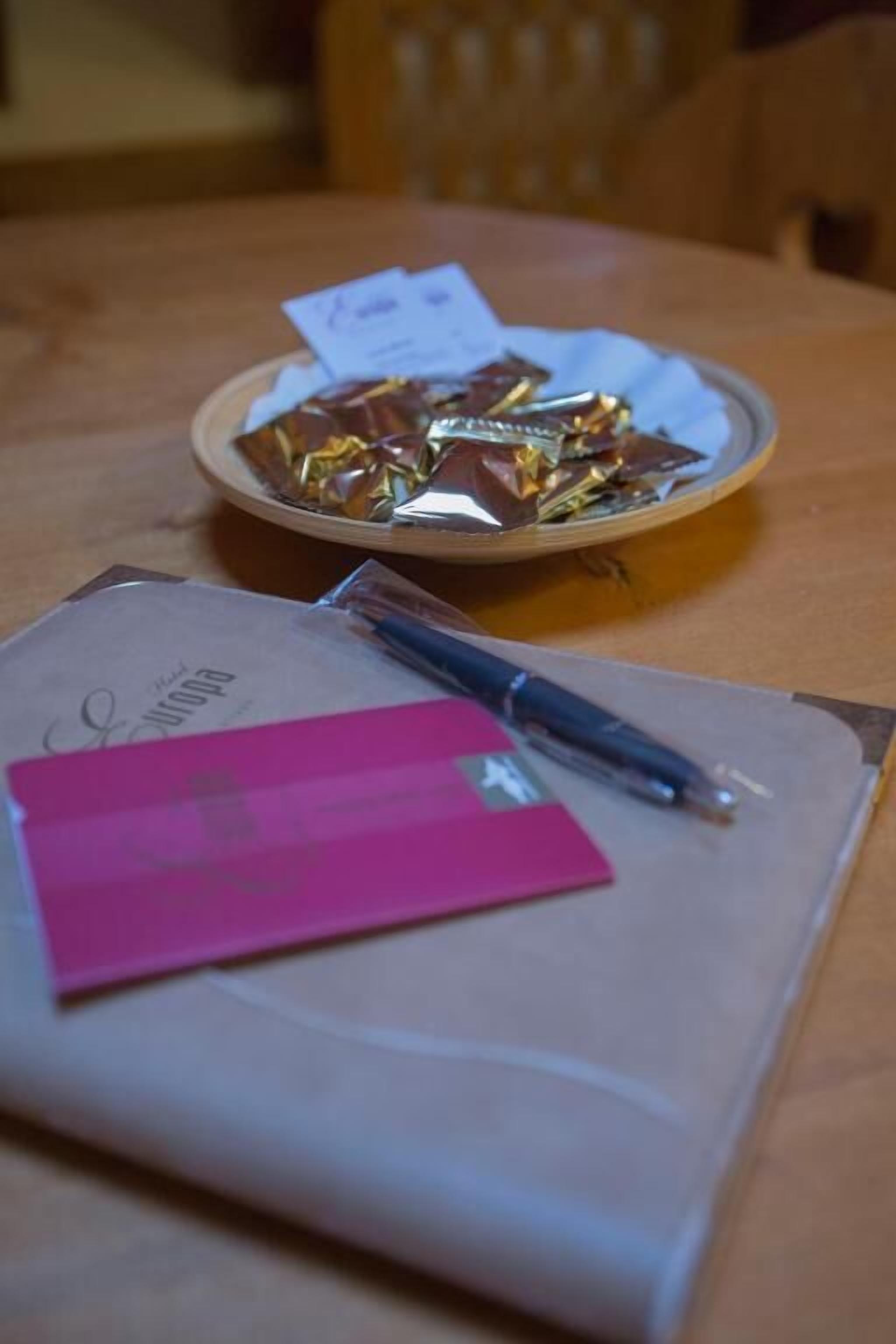 A table with a notebook, a pen, and a bowl of chocolates.
