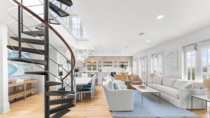 A spacious living area with a modern staircase, a dining area, and a kitchen. - Luxury Renovation in Seaside w/Expansive Rooftop Deck, Gulf Views, & 3 Kings (Santa Rosa Beach)