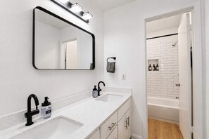 Une salle de bain avec un double lavabo, un grand miroir et un espace douche.