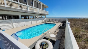 A swimming pool with a view of the ocean, surrounded by a white fence and deck chairs. - BEACHFRONT, 5BR/5BA, Sleeps up to 12 w/ Elevator & Pool! (St. George Island)