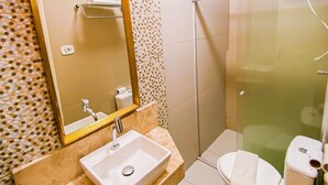 A bathroom with a sink, mirror, toilet, and shower.