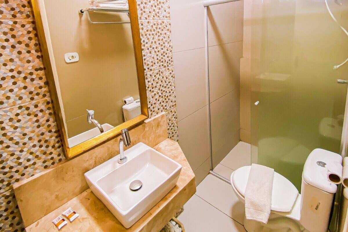 Ein Badezimmer mit Waschbecken, Spiegel, Toilette und Dusche.