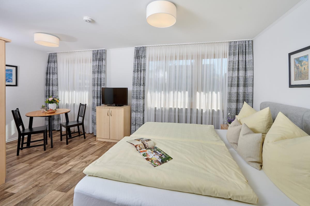 Une chambre d’hôtel avec un lit, une télévision, un bureau avec une chaise et des rideaux.