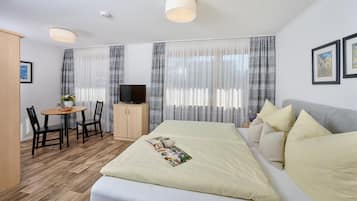 A hotel room with a bed, a TV, a desk with a chair, and curtains.