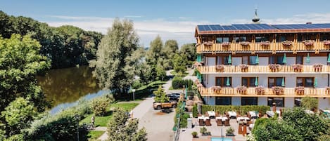 Un hotel con piscina, un lago y una zona boscosa.