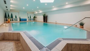 An indoor swimming pool with a tiled floor, a ceiling light, and a wall mural.
