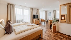 A hotel room with two beds, a desk, a chair, a TV, and a large mirror.