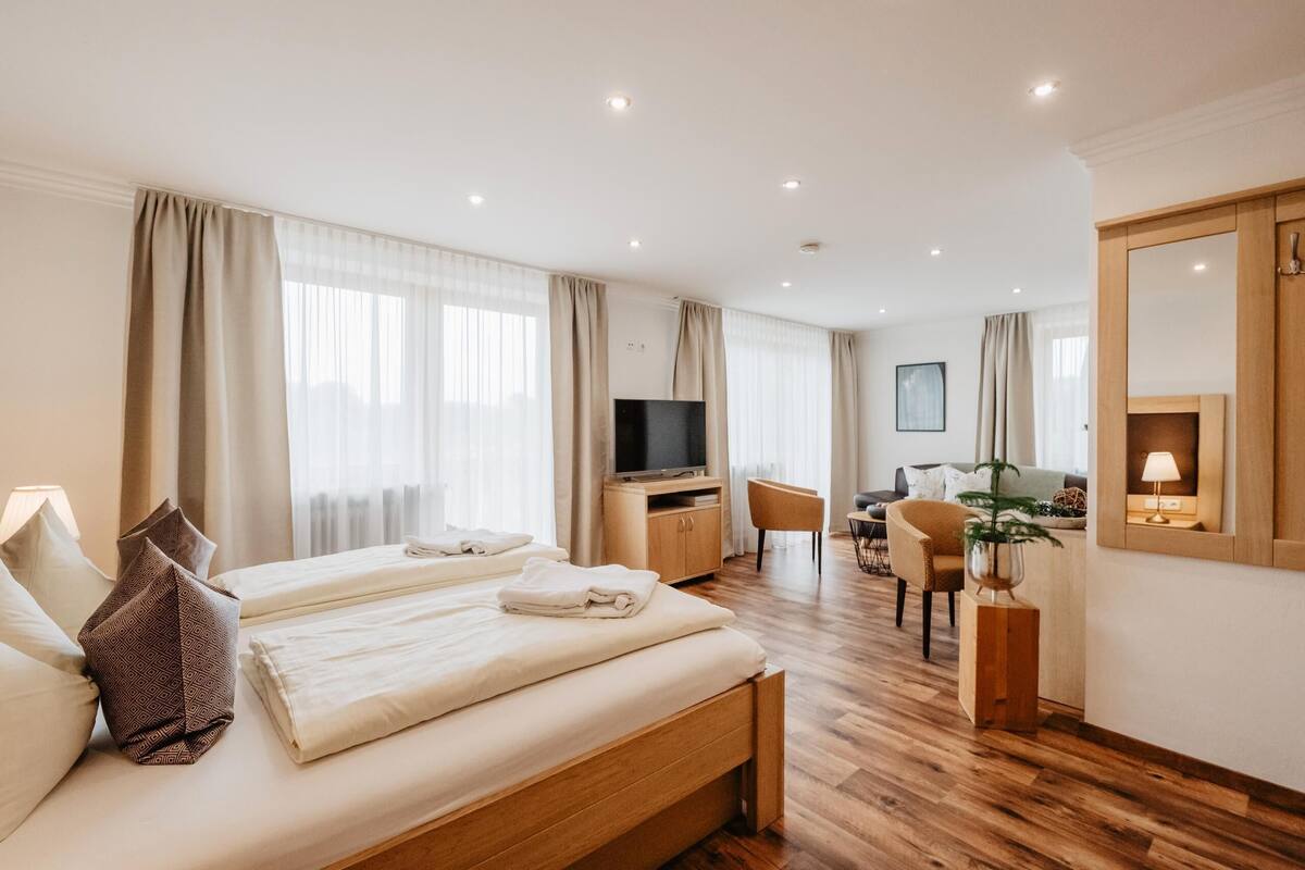 Une chambre d’hôtel avec deux lits, un bureau, une chaise, une télévision et un grand miroir.