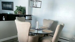 A dining area with a round table, four chairs, a hanging light fixture, and a kitchen in the background. - Beautiful Home in South Park. Walk to UD Campus, Miami Valley Hospital, Downtown (Dayton)