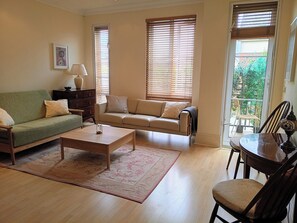 A living room with a sofa, a coffee table, a lamp, and a dining table with chairs. - Luxury Apartment in London, Richmond Kew with Free Underground Parking  (Richmond)