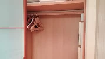 A walk-in closet with a sliding door, a hanging rack, and shelves for folded clothes.