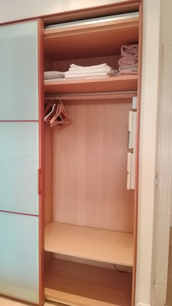 Een inloopkast met schuifdeur, een kledingroede en planken voor opgevouwen kleding.