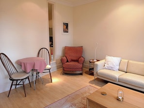 A living room with a wooden floor, a red and white checkered table, a brown chair, a patterned armchair, a white sofa, and a small table with a lamp. - Luxury Apartment in London, Richmond, Kew with Free Underground Parking  (Richmond)