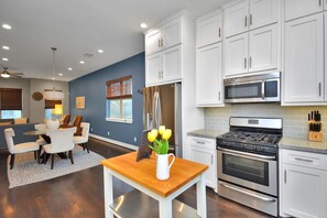 A modern kitchen with white cabinets, stainless steel appliances, and a dining area with a wooden table and chairs.