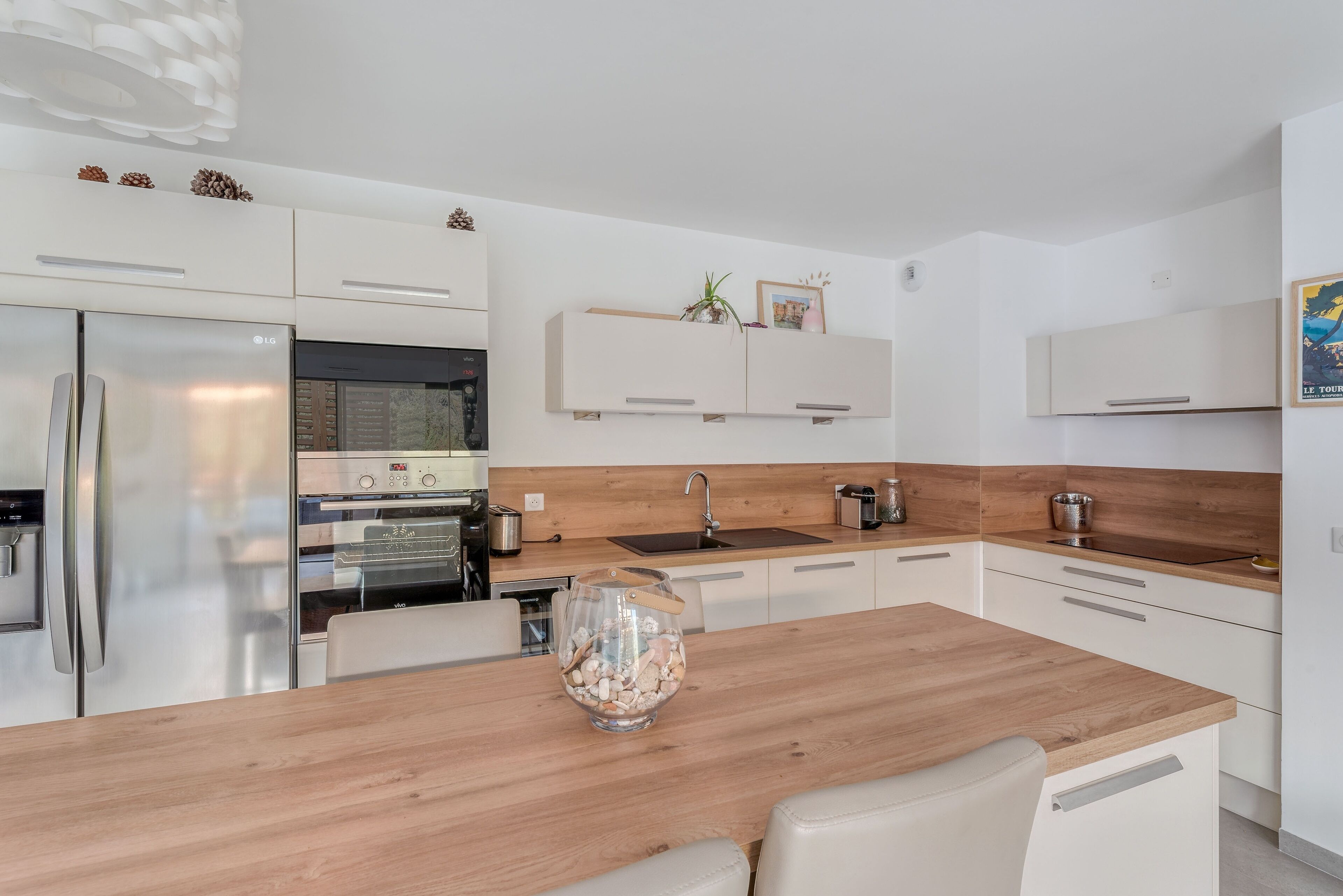 Une cuisine moderne avec des meubles blancs, un plan de travail en bois et un four encastré.