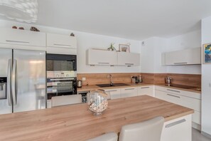 A modern kitchen with white cabinetry, a wooden countertop, and a built-in oven.