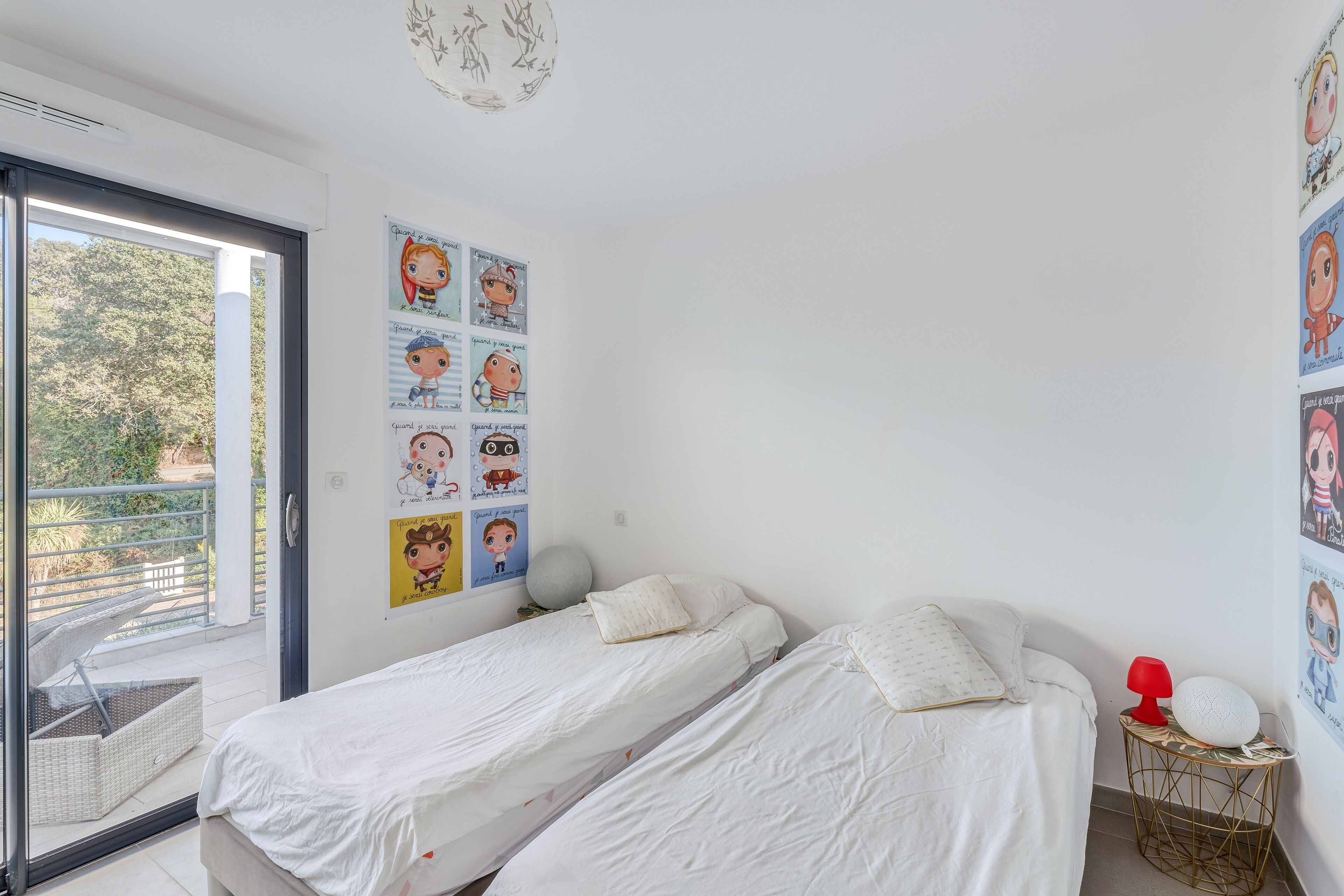 Een slaapkamer met twee bedden, een raam en een muur versierd met kinderposters.