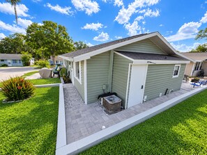 A single-story mobile home with a covered porch, a small attached garage, and a paved driveway.