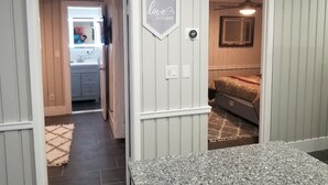 A hallway with a vanity, a bed, and a wall-mounted sign.