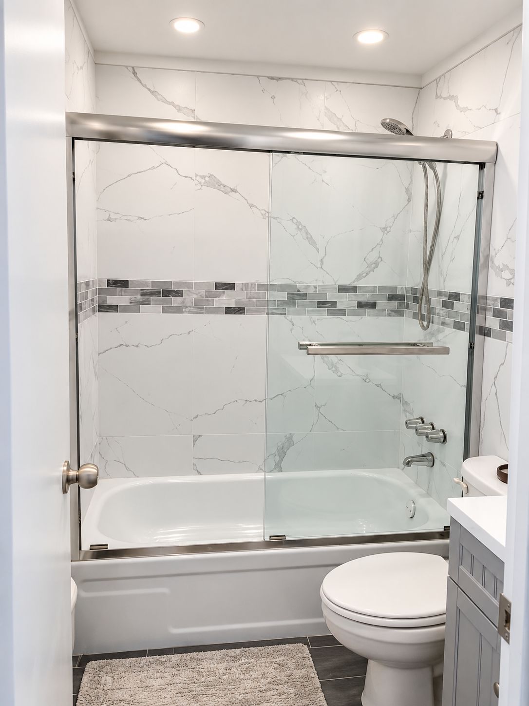 Een moderne badkamer met een douchecabine, een wit bad en een toilet.
