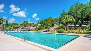 A rectangular swimming pool with a clear blue water, surrounded by a paved deck.